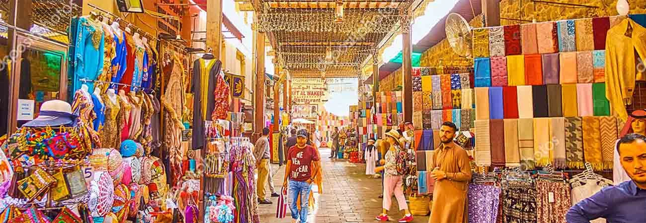DUBAI, UAE - MARCH 2, 2020: The narrow alleyway of Bur Dubai Grand Souq (bazaar, market), lined with stalls, offering garment, souvenirs, cashmere scarfs, embroidered pillowcases etc, on March 2 in Dubai